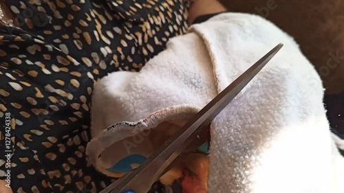 Close-up of the hands of a woman using scissors to cut fabric. Cutting cotton hoodie.