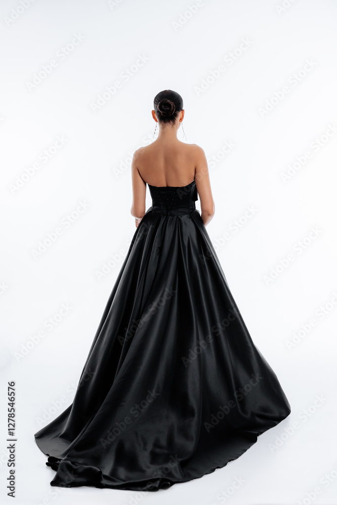 Beautiful tender brunette girl in a black dress with a train. Evening dress isolated on a white background Beautiful tender brunette girl in a black dress with a train. Evening dress isolated on a white background