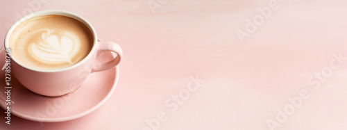A top-view shot of a cappuccino in a pastel-colored cup, featuring a delicate heart-shaped latte art design. The coffee sits against a soft, textured background