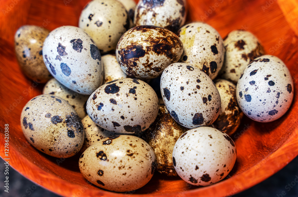 Obraz premium A close-up of quail eggs lying in a wooden plate.