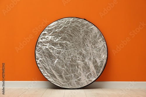 One light reflector near orange wall indoors. Photo studio equipment