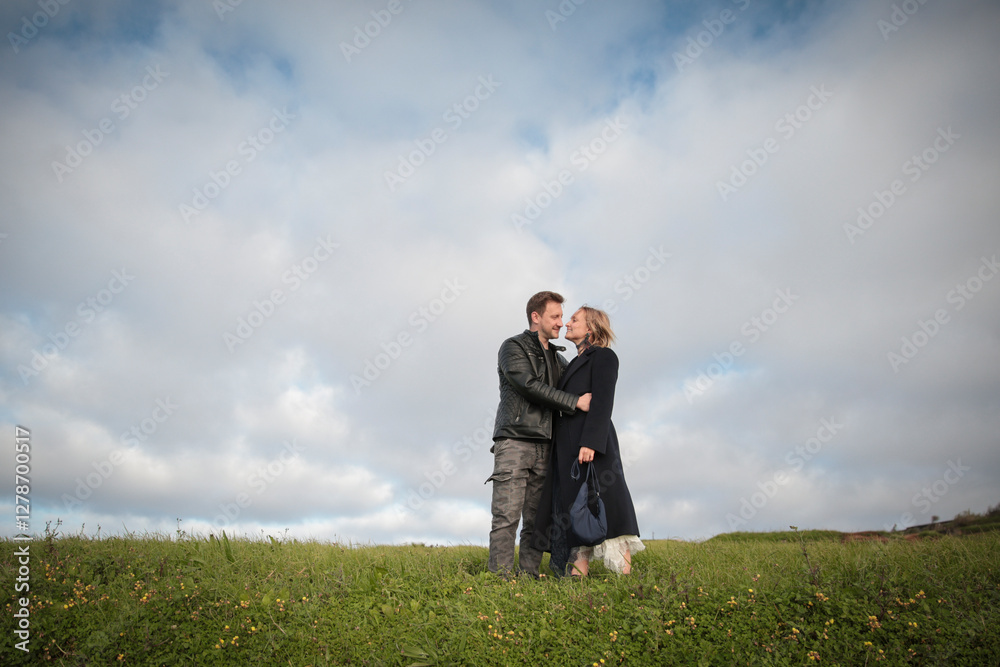 Couple embracing in a meadow under cloudy sky in madeira island Couple embracing in a meadow under cloudy sky in madeira island