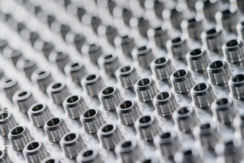 close-up view of numerous small, cylindrical metal components arranged in a precise pattern.