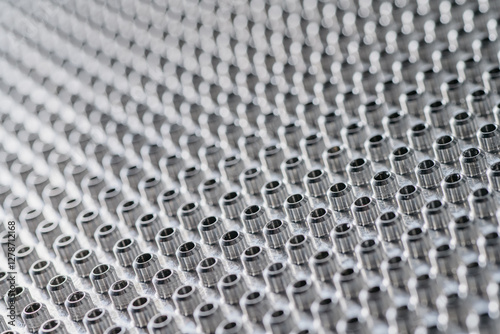 close-up view of numerous small, cylindrical metal components arranged in a precise pattern.