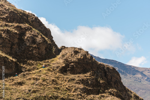 a group of native aymara people walking and hiking in the heights in the andean mountain range in bolivian town charazani showing the vastness of space photo