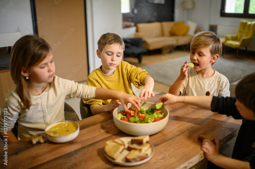 Children enjoy a hearty meal at the table, eating pea soup with croutons and fresh salad. They savor their food with appetite, creating a warm and cozy family dining atmosphere. Children enjoy a hearty meal at the table, eating pea soup with croutons and fresh salad. They savor their food with appetite, creating a warm and cozy family dining atmosphere.