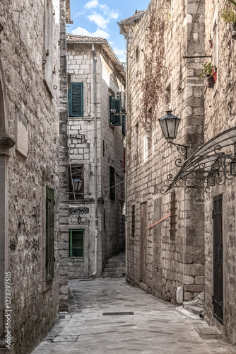 Narrow, historic street in Kotor, Montenegro, lined with stone buildings and traditional shutters. Charming alley reflects the medieval architecture of the Old Town, inviting exploration of local life