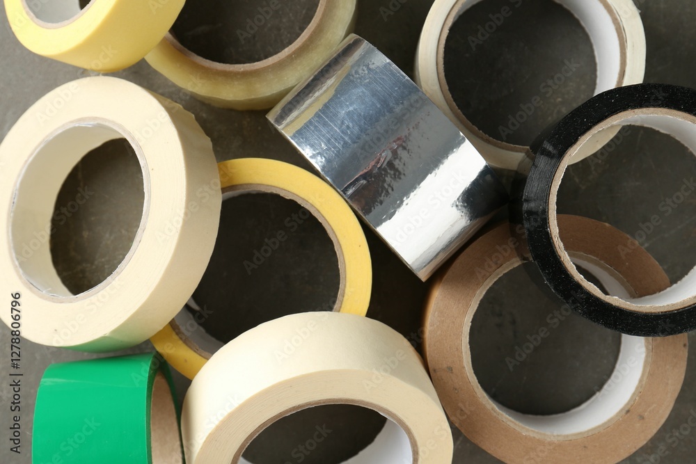 Rolls of different adhesive tapes on grey table, flat lay Rolls of different adhesive tapes on grey table, flat lay