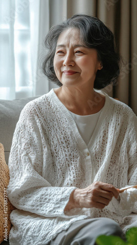 Japanese woman grandmother smiling sitting relaxing home, white kitted cardigan simple elegant fashion, healthy active senior lifestyle concept