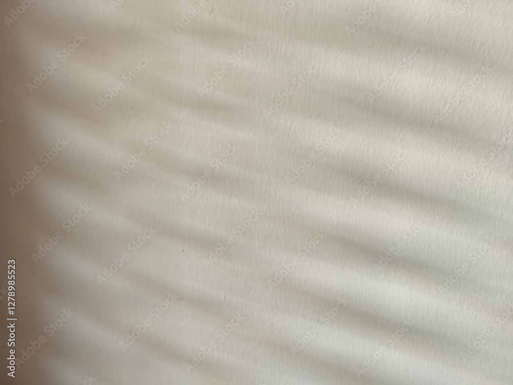 Naklejka premium white fabric texture Light passes through the blinds and hits the cream-white wall, creating patterns and shadows.