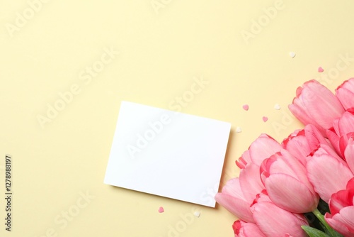 Beautiful fresh tulips and white paper czrd on color background photo