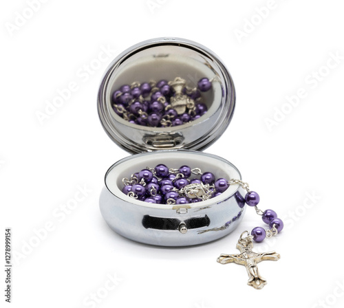 A rosary with purple beads is stored in a silver metal jewelry box.
