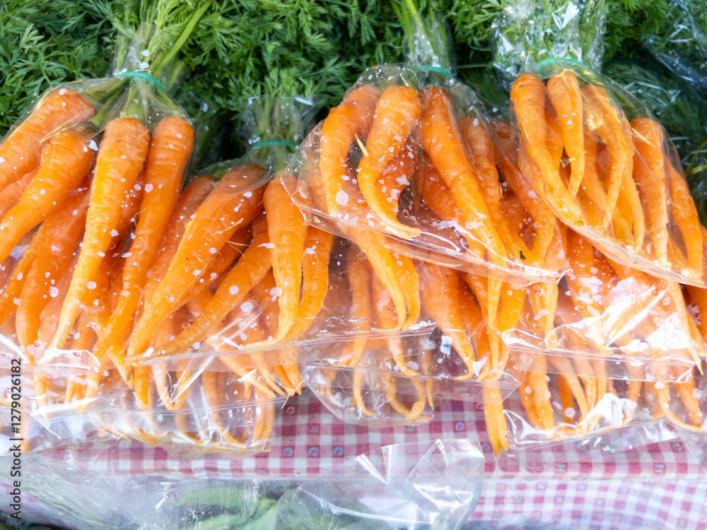 Fresh Organic Baby Carrots Packed in Plastic Bags at Local Market.
