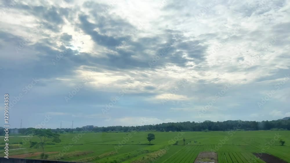 landscape with clouds, blue sky, and ricefield in Java pov from a train landscape with clouds, blue sky, and ricefield in Java pov from a train