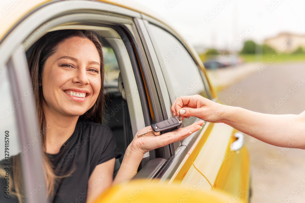 A smiling woman sitting in a yellow car receives a set of keys from another person, symbolizing a car purchase, rental, or ownership transfer.