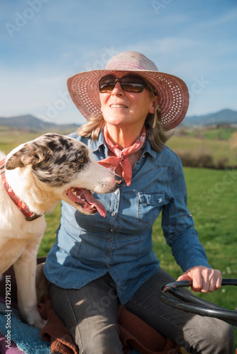 Celebrating international workers' day, a farmer enjoys a sunny day on her tractor with her dog