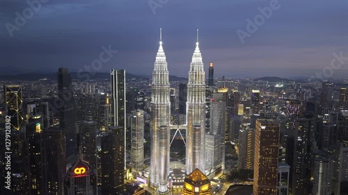 ProRes HDR drone footage of Petronas Towers in downtown Kuala Lumpur, Malaysia as night sets in. Cinematic aerial shot orbiting to the left.