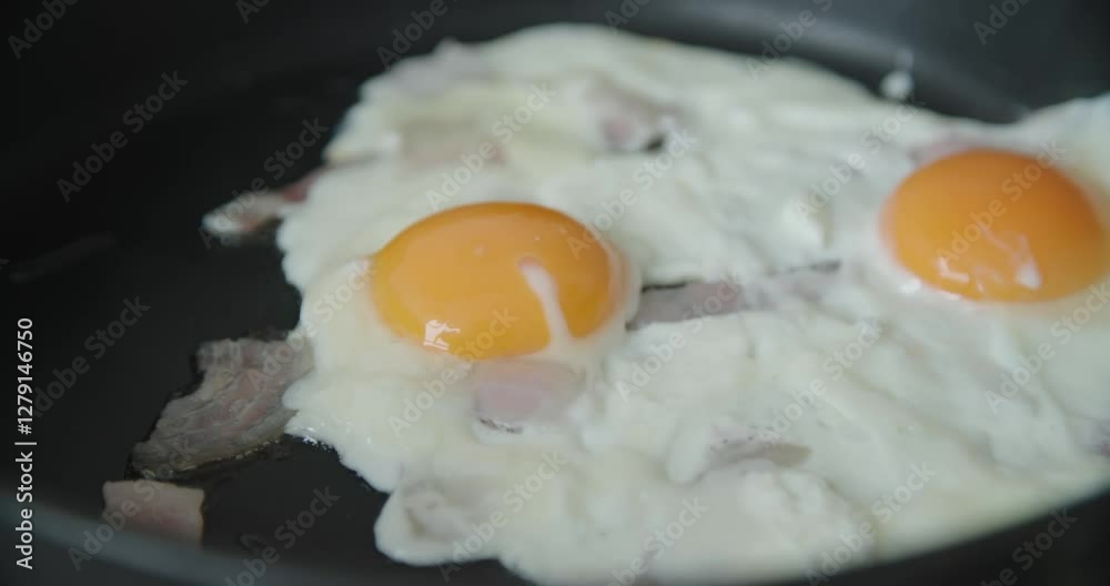 Deliciously prepared fried egg featuring perfectly cooked yolk accompanied by crispy, savory bacon Deliciously prepared fried egg featuring perfectly cooked yolk accompanied by crispy, savory bacon