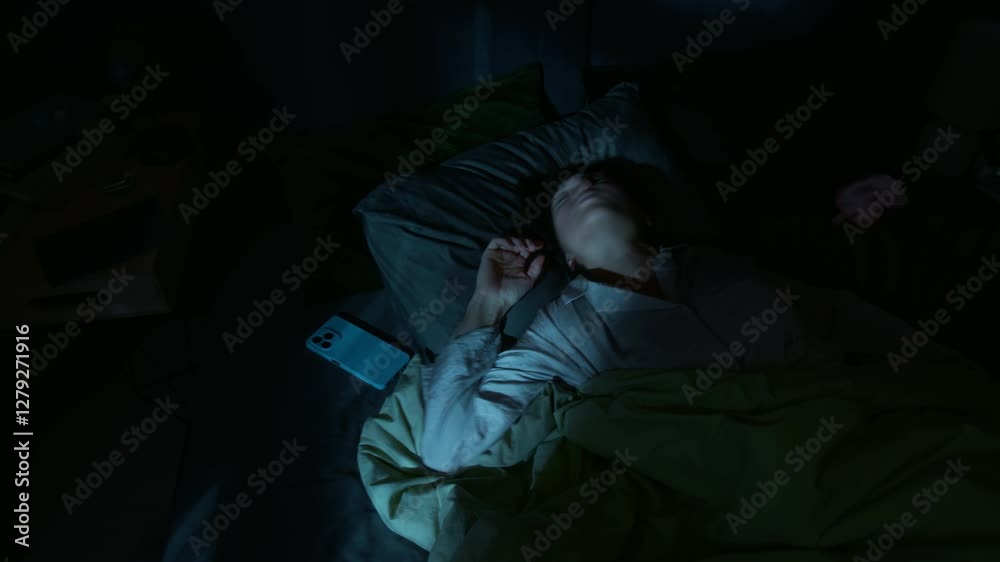 Young woman tossing and twitching, having intense nightmare, while sleeping in bed at night Young woman tossing and twitching, having intense nightmare, while sleeping in bed at night