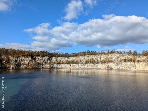 Crystal Clear Lake Surrounded by Rocky Cliffs and Autumn Trees