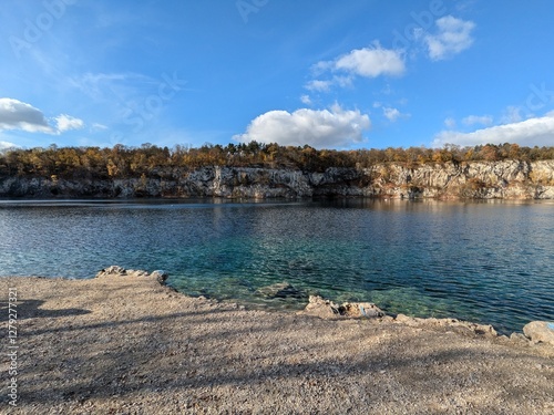 Crystal Clear Lake Surrounded by Rocky Cliffs and Autumn Trees