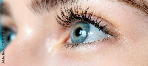Close-up of a young woman's eye, looking off to the side, with long eyelashes; soft background. Ideal for beauty, vision, or healthcare advertising