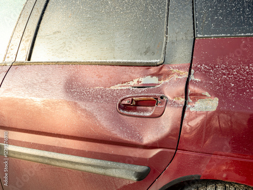 Red car door dented after accident, car hit. Impact damage. Damaged rear door of car, dent after road collision