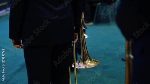 Musicians of a military orchestra prepare to perform in formal wear at a concert venue during an evening event