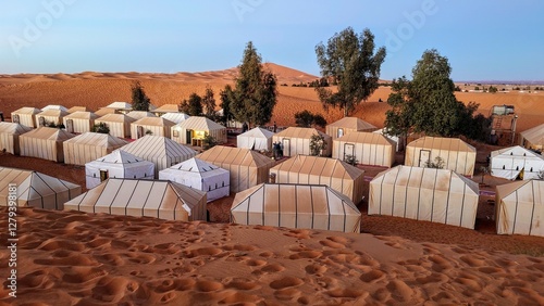 Desert camp with traditional tents in the sand dunes of Merzouga, Morocco, under a clear blue sky