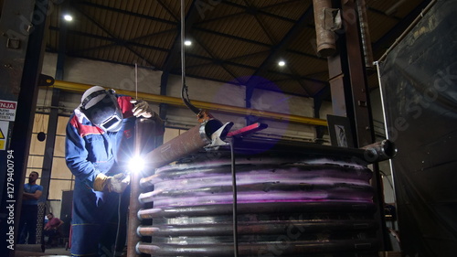 A welder works with an electrode, creating sparks and a glowing arc. The image highlights the welding process, showcasing precision and skill in metalworking and industrial craftsmanship.