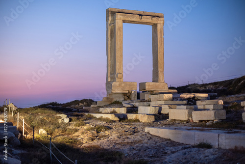 People watch sunset at Portara gate of the Temple of Apollo at Naxos island in the Cyclades, Aegean Sea, Greece