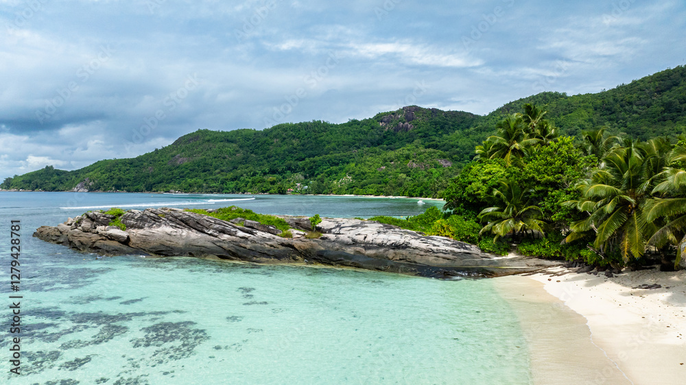 Rocky shoreline surrounded by turquoise waters and a dense tropical forest. Seychelles, Mahe. Anse Forbans. Rocky shoreline surrounded by turquoise waters and a dense tropical forest. Seychelles, Mahe. Anse Forbans.
