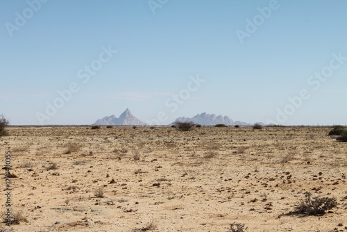 Panormaic view of Spitzkoppe mountain in Namibia with surrounding plains as seen from a distance. Scenic African landscape. photo