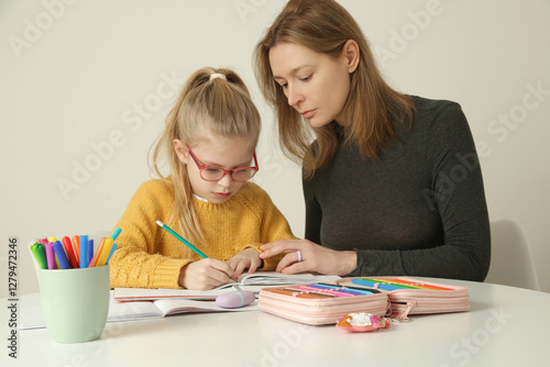 Parental assistance. Mother helping her little daughter to prepare homework at home. Home education, homeschooling concept.	