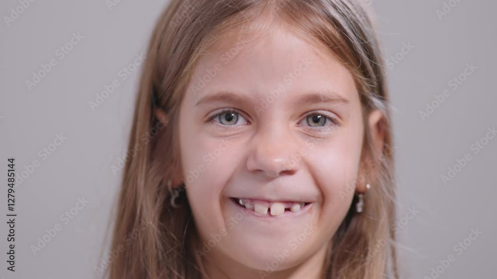 Little girl playfully pulling her cheeks and showing metallic teeth, making a funny face, closeup portrait, looking at camera with a cheerful expression Little girl playfully pulling her cheeks and showing metallic teeth, making a funny face, closeup portrait, looking at camera with a cheerful expression