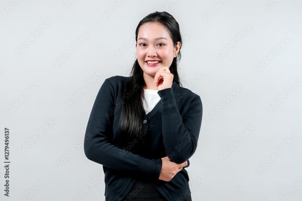 A thoughtful young woman in a black cardigan rests her chin on her hand, smiling gently against a light gray background, conveying contemplation and positivity. A thoughtful young woman in a black cardigan rests her chin on her hand, smiling gently against a light gray background, conveying contemplation and positivity.