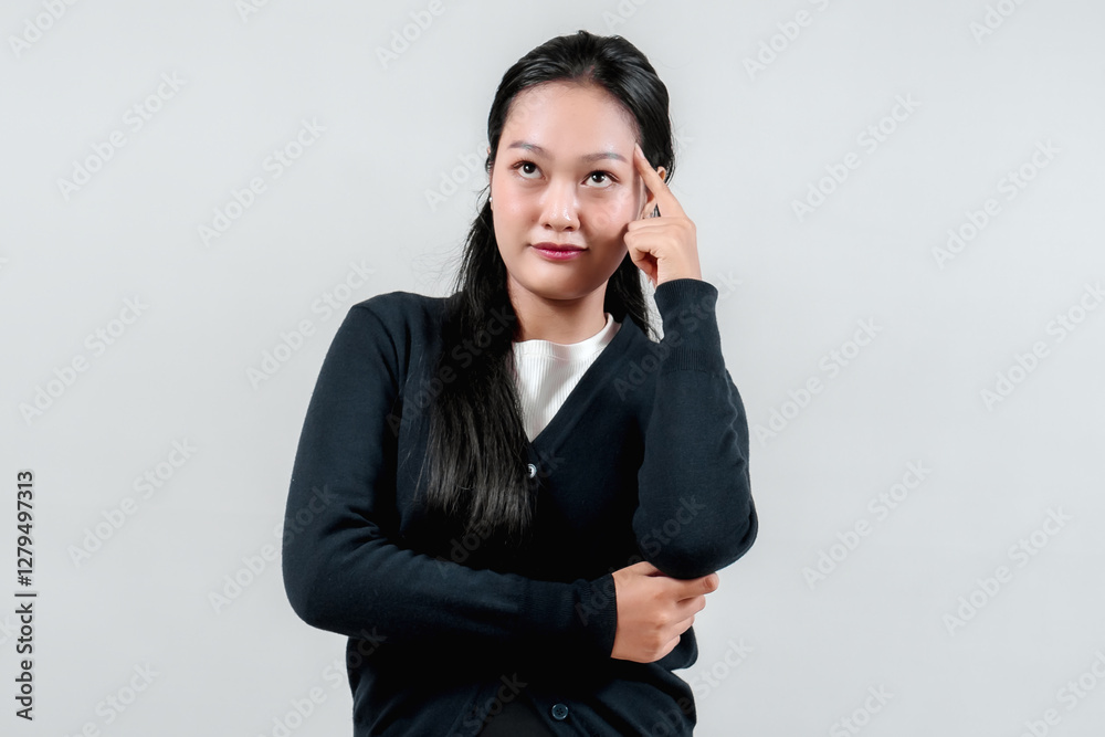 A young woman in a black cardigan thoughtfully touches her temple, smiling gently against a light gray background, embodying contemplation and confidence. A young woman in a black cardigan thoughtfully touches her temple, smiling gently against a light gray background, embodying contemplation and confidence.