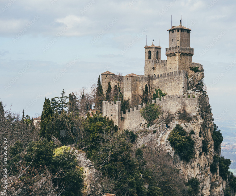 Fototapeta premium castle tower defence in the uphill with clouds around in spring san marino city