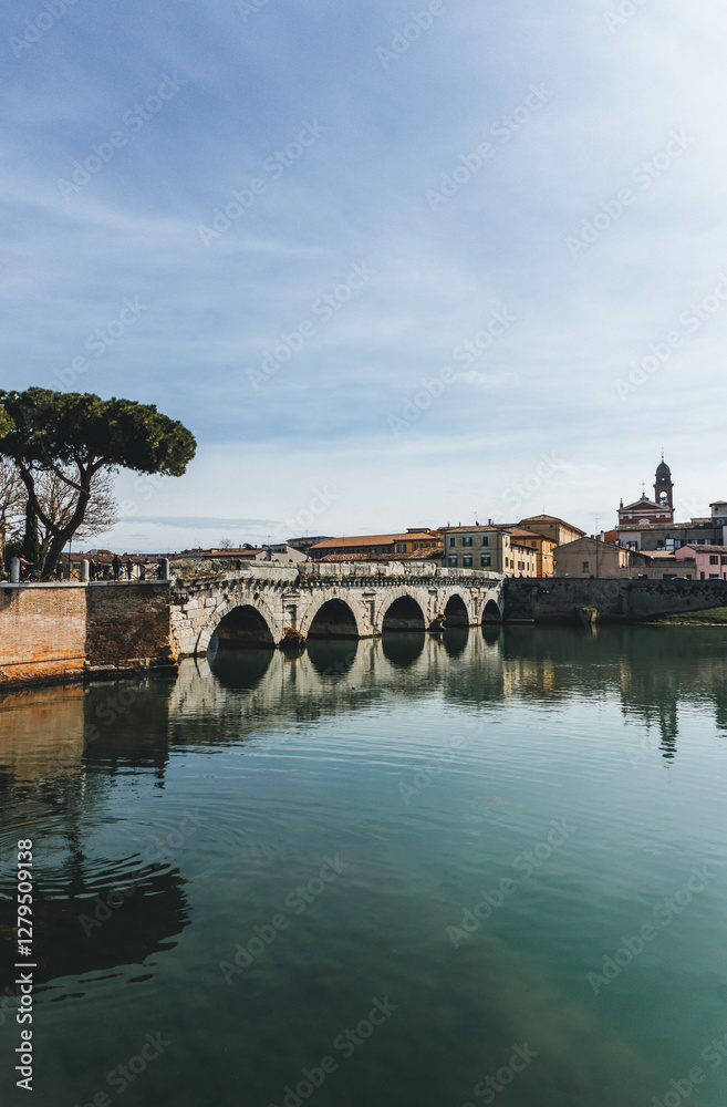 Obraz premium anicent roman bridge from first century in rimini on clear sky with water refelction