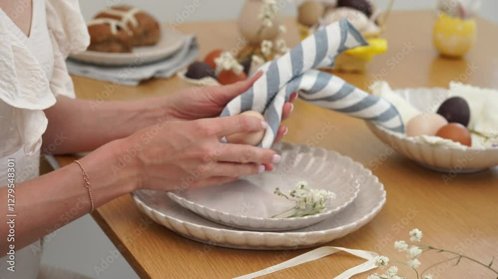 Woman putting an egg in the napkin to make an easter bunny from napkin with a dried flowers Woman putting an egg in the napkin to make an easter bunny from napkin with a dried flowers