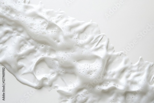 Textured white foam spreads diagonally across a light surface photo