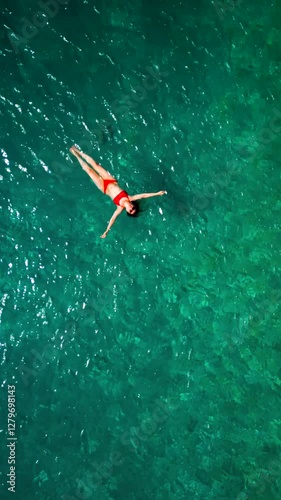 Wallpaper Mural Woman in red swimsuit lays on her back in the clear sea, top down view Torontodigital.ca