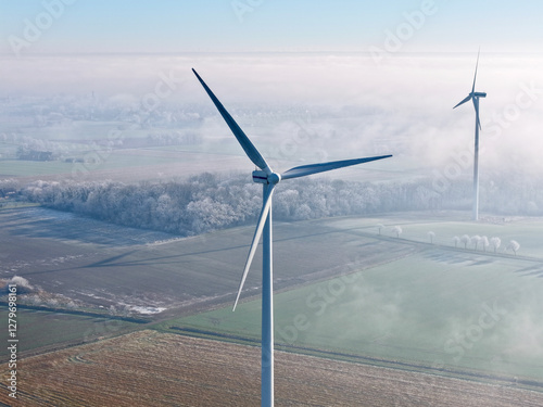 Aerial view of a wind turbine in a winter landscape with sun and deep fog over the fields, wind energy, renewable energies, energy transition, climate protection