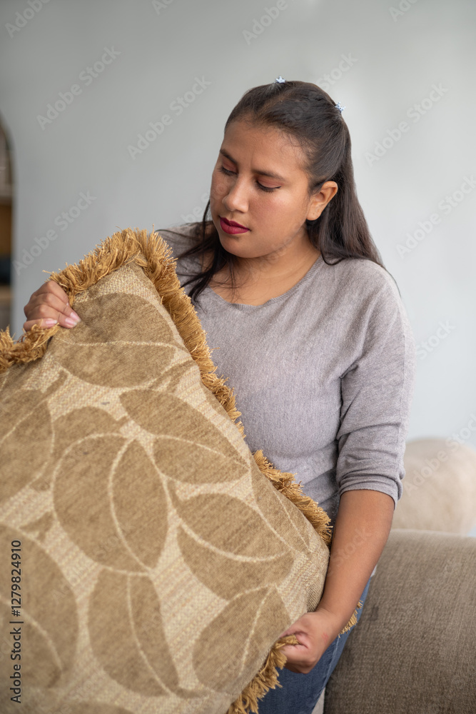 A housekeeper shakes the sofa cushions to refresh the living room, ensuring a clean and tidy space. The task adds a polished touch to the home environment. A housekeeper shakes the sofa cushions to refresh the living room, ensuring a clean and tidy space. The task adds a polished touch to the home environment.