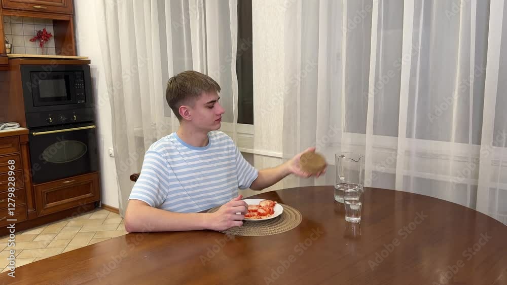 Young man sits at a table with a slice of pizza and glass of water. He looks relaxed in a cozy kitchen setting. Young man sits at a table with a slice of pizza and glass of water. He looks relaxed in a cozy kitchen setting.