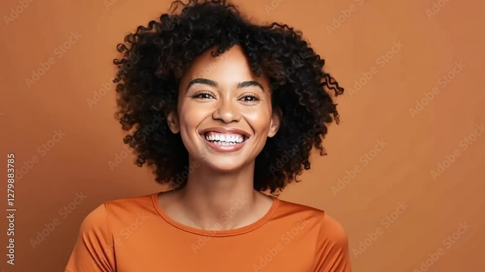 Portrait video style with a front-facing camera angle, capturing a joyful expression against a warm, orange background. Portrait video style with a front-facing camera angle, capturing a joyful expression against a warm, orange background.
