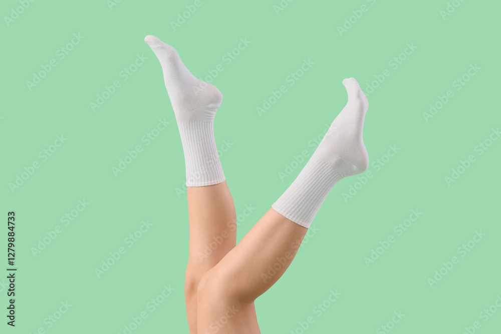Legs of young woman in stylish white socks on green background Legs of young woman in stylish white socks on green background