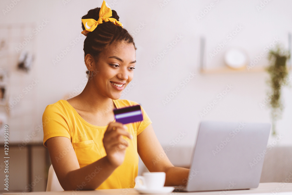 Online Shopping Concept. Portrait of smiling african american woman holding credit card in hand and using laptop, sitting at desk, typing on keyboard, blurred background, selective focus. Ecommerce Online Shopping Concept. Portrait of smiling african american woman holding credit card in hand and using laptop, sitting at desk, typing on keyboard, blurred background, selective focus. Ecommerce