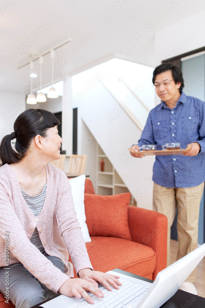 リビングでパソコンを見る夫婦