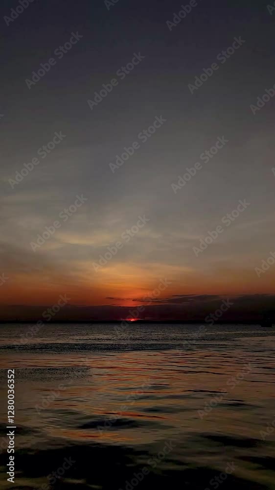 Vertical Video: Calm Ocean Water Reflecting a Vibrant Cloudy yet Colorful Sky at Sunset Vertical Video: Calm Ocean Water Reflecting a Vibrant Cloudy yet Colorful Sky at Sunset